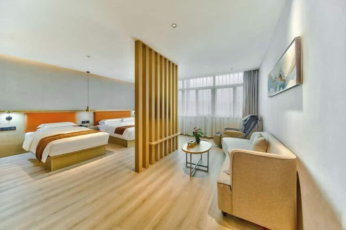 A hotel room with a bed, a sofa, a small table, and a window.