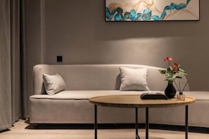 A modern living room with a sofa, a round coffee table, and a vase with flowers. - Oukai Hotel (Hangzhou)