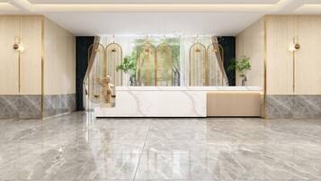 A reception area with a marble floor, a reception desk, and a large window with a view of greenery.