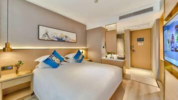 Quarto de hotel com cama grande, mesas de cabeceira, televisão de tela plana, espelho e porta com placa.