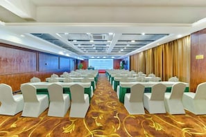 A conference room with rows of tables and chairs, a carpeted floor, and a stage at the front. - Oukai Hotel (Hangzhou)