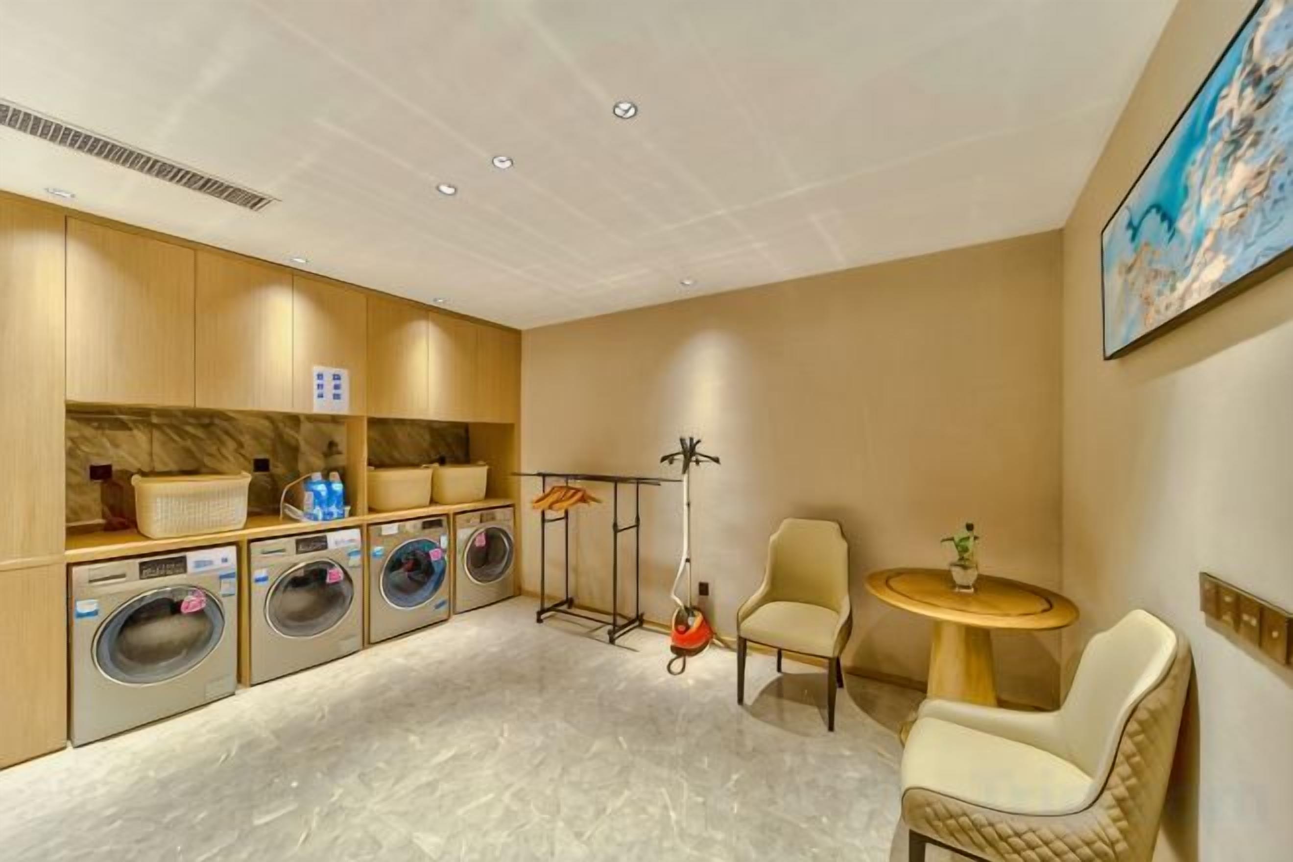 A hotel room with a washing station, a seating area, and a painting on the wall.