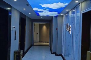 A hallway with a ceiling mural, a door with a light fixture, and a marble wall. - Oukai Hotel (Hangzhou)
