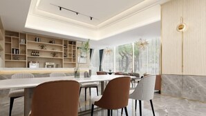 A modern dining area with a long table, several chairs, and a built-in bookshelf. - Oukai Hotel (Hangzhou)