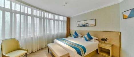 A hotel room with a large bed, a bench, a bedside table, and a window with curtains.