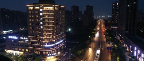 A multi-story hotel with a modern design, located in an urban setting with a busy street in the foreground.