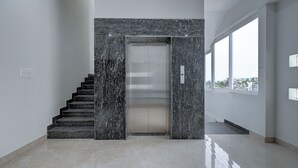 A modern elevator with a marble wall and a staircase leading to it. - Hotel Cloud 9 Luxury stay - Mysore (Mysore)