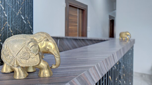 A golden elephant statue on a modern counter with a patterned wall and a wooden door in the background. - Hotel Cloud 9 Luxury stay - Mysore (Mysore)