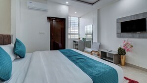 A modern hotel room with a large bed, a desk, a chair, and a TV mounted on the wall. - Hotel Cloud 9 Luxury stay - Mysore (Mysore)