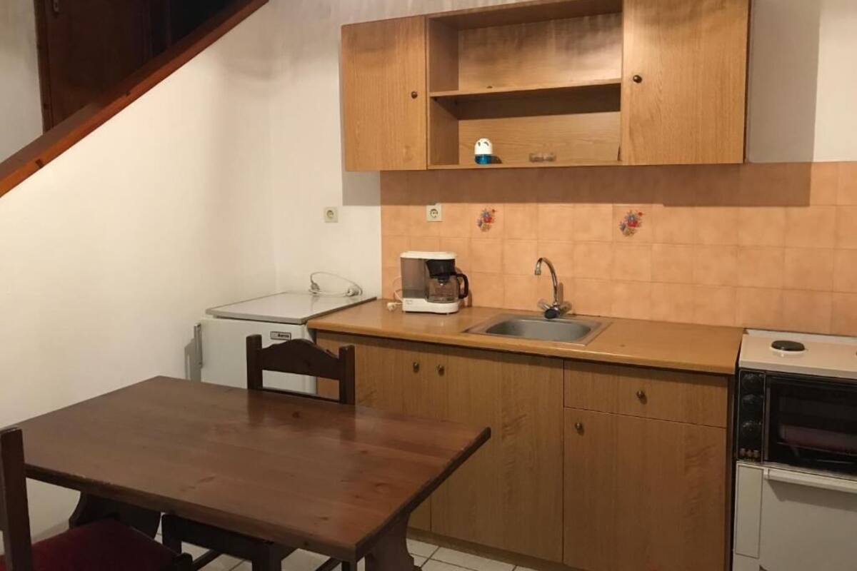 A compact kitchen with wooden cabinets, a sink, a coffee maker, and a microwave.