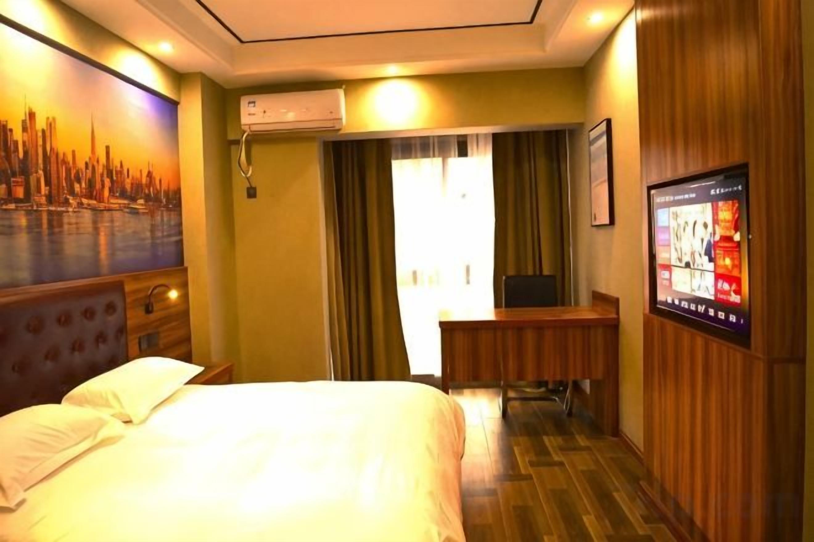Een hotelkamer met een bed, een bureau, een televisie en een stadsgezicht schilderij aan de muur.