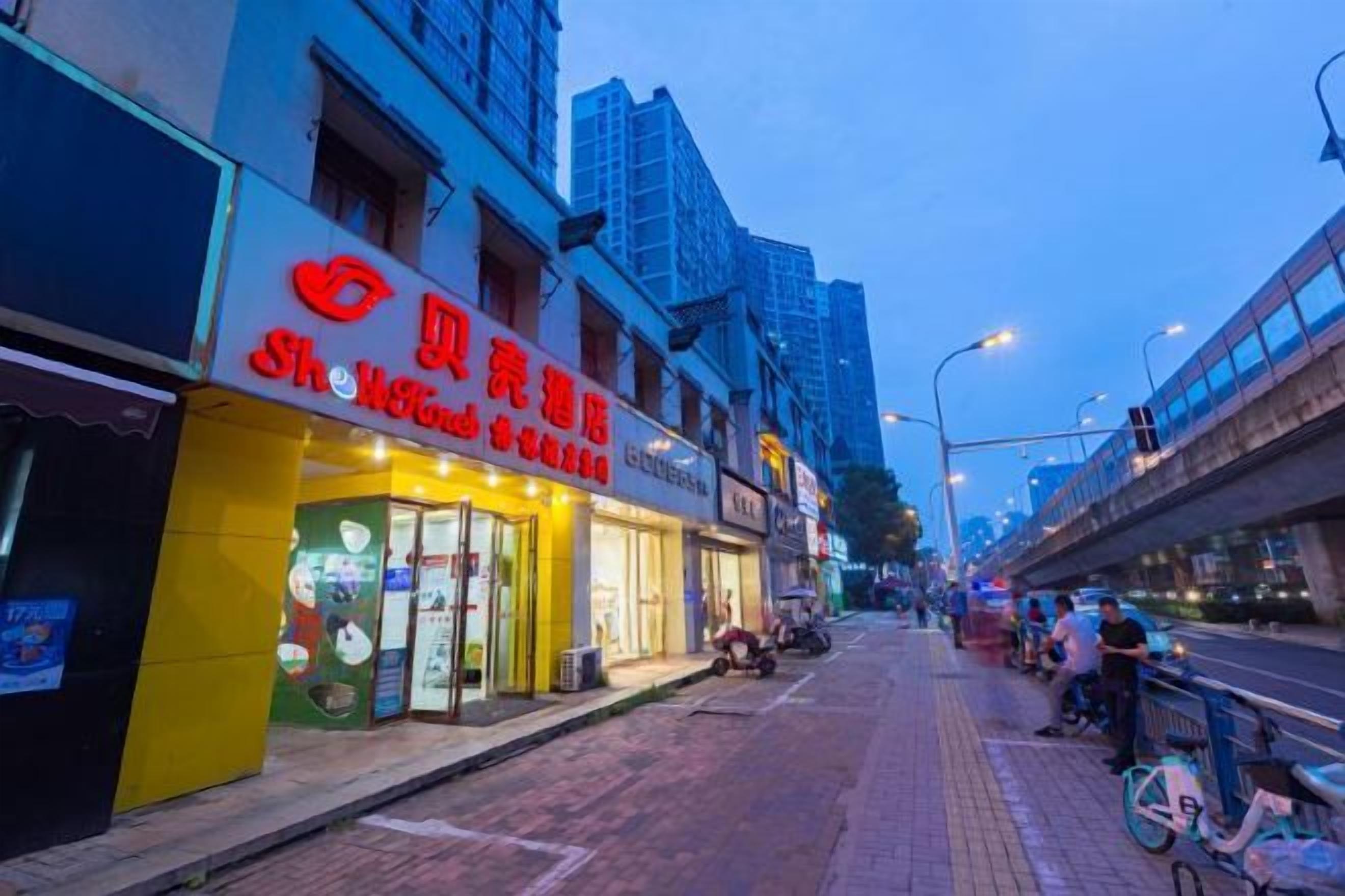 A street with storefronts, including one with a red sign and another with a yellow awning.