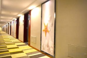 A hotel corridor with doors on the left and a large poster on the right wall. - Shell Hotel (Hefei Maanshan Road Hegongda Subway Station) (Hefei)