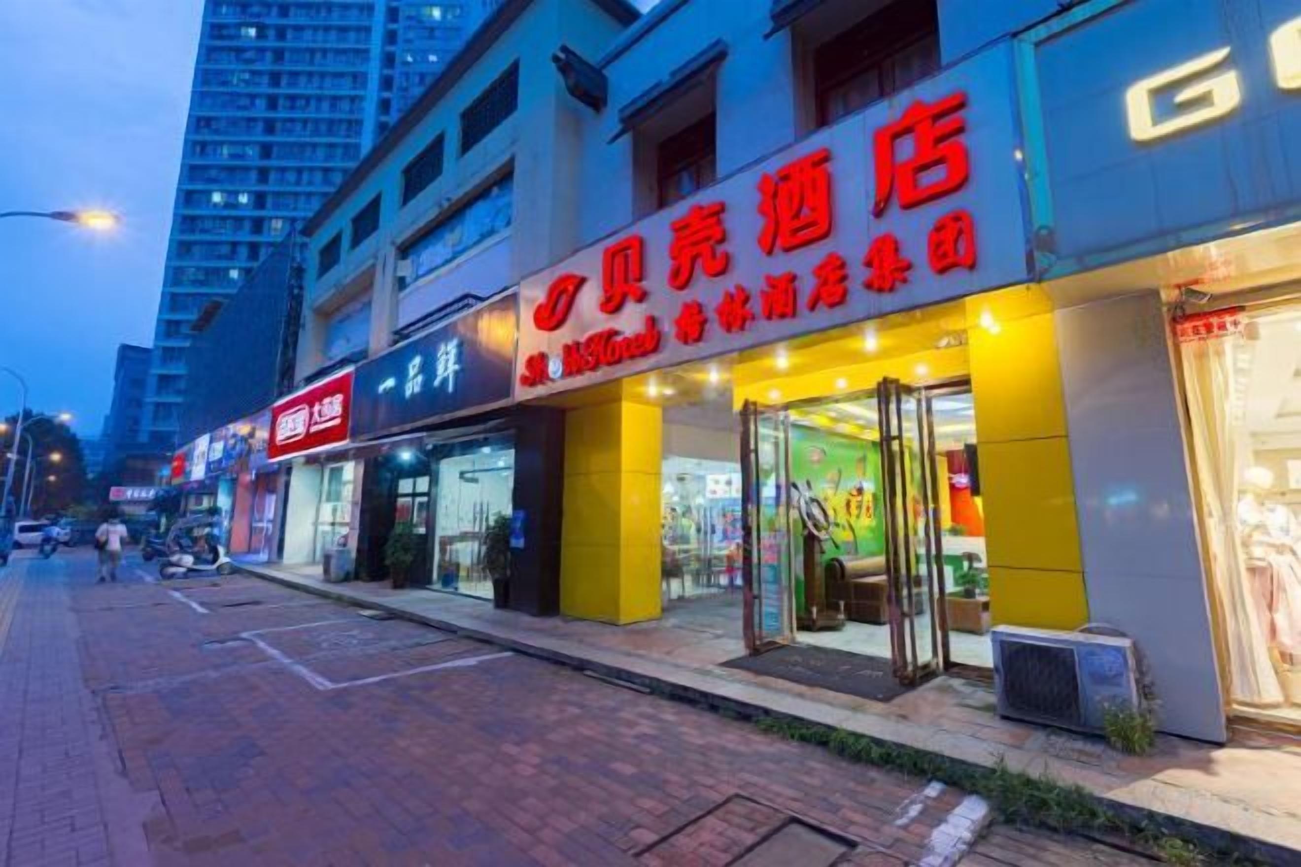 A storefront with illuminated signage, a visible entrance, and a pedestrian walkway.
