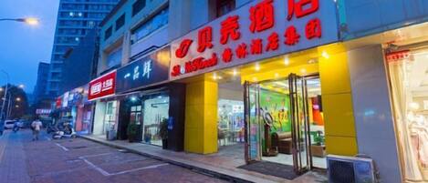 A storefront with illuminated signage, a visible entrance, and a pedestrian walkway.
