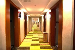 A hotel hallway with doors on both sides, a checkered floor, and signs above the doors. - Shell Hotel (Hefei Maanshan Road Hegongda Subway Station) (Hefei)