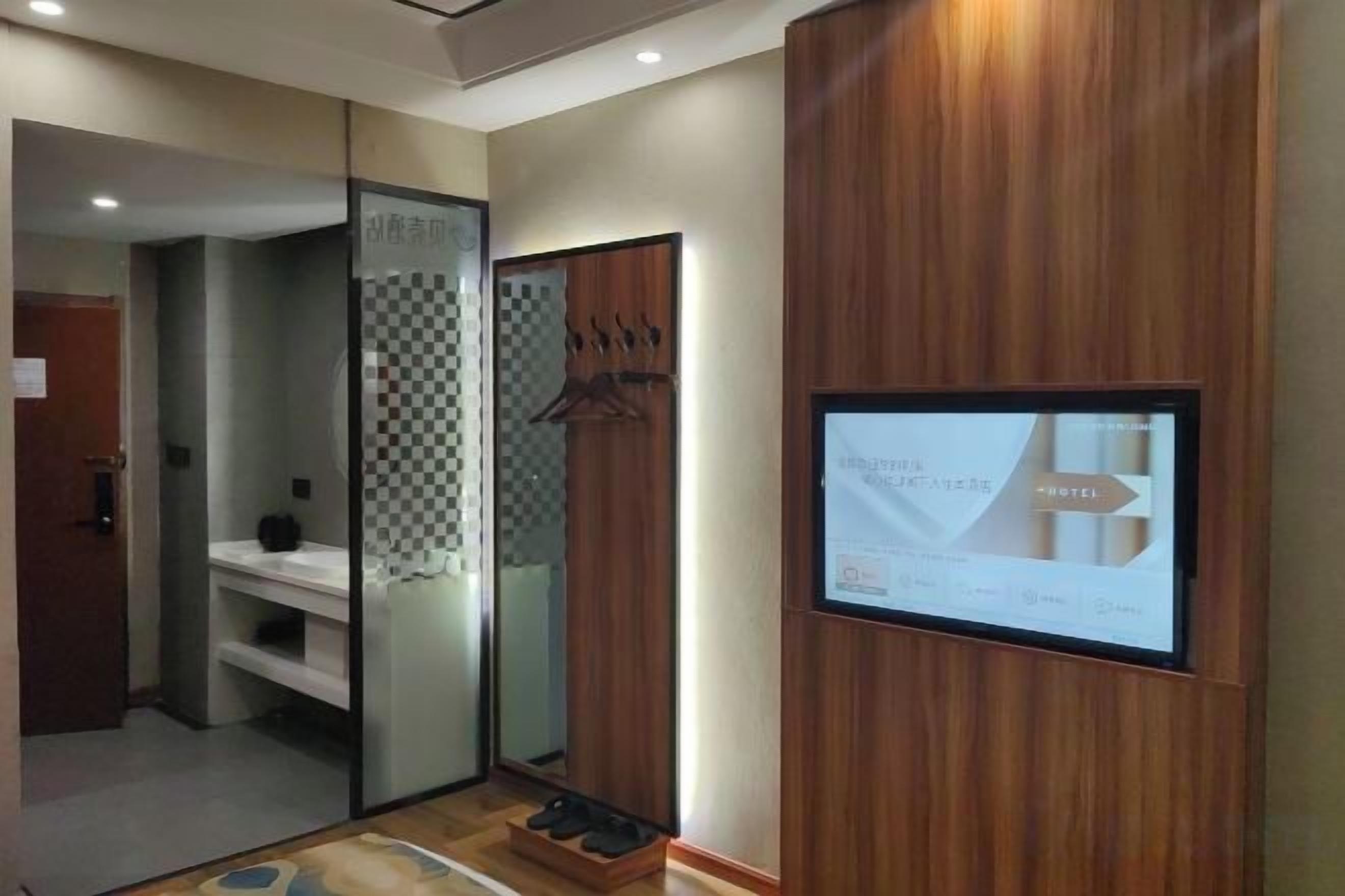 A hotel room with a wooden panel wall, a digital display, and a mirror.