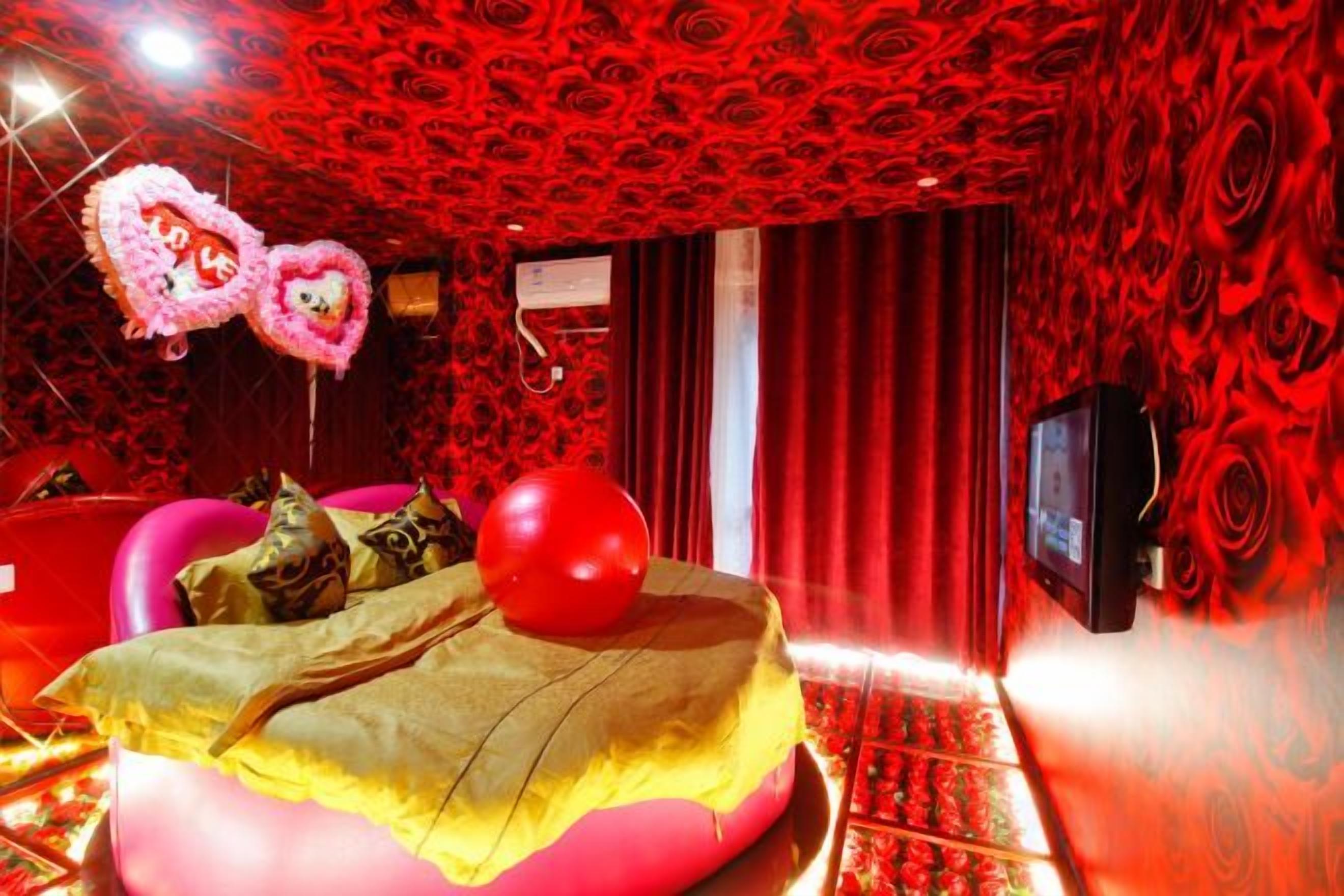 Una habitación con una cama, un televisor y una pared con diseño rojo.