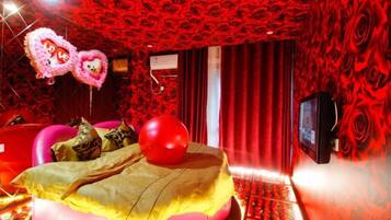 Una habitación con una cama, un televisor y una pared con diseño rojo.