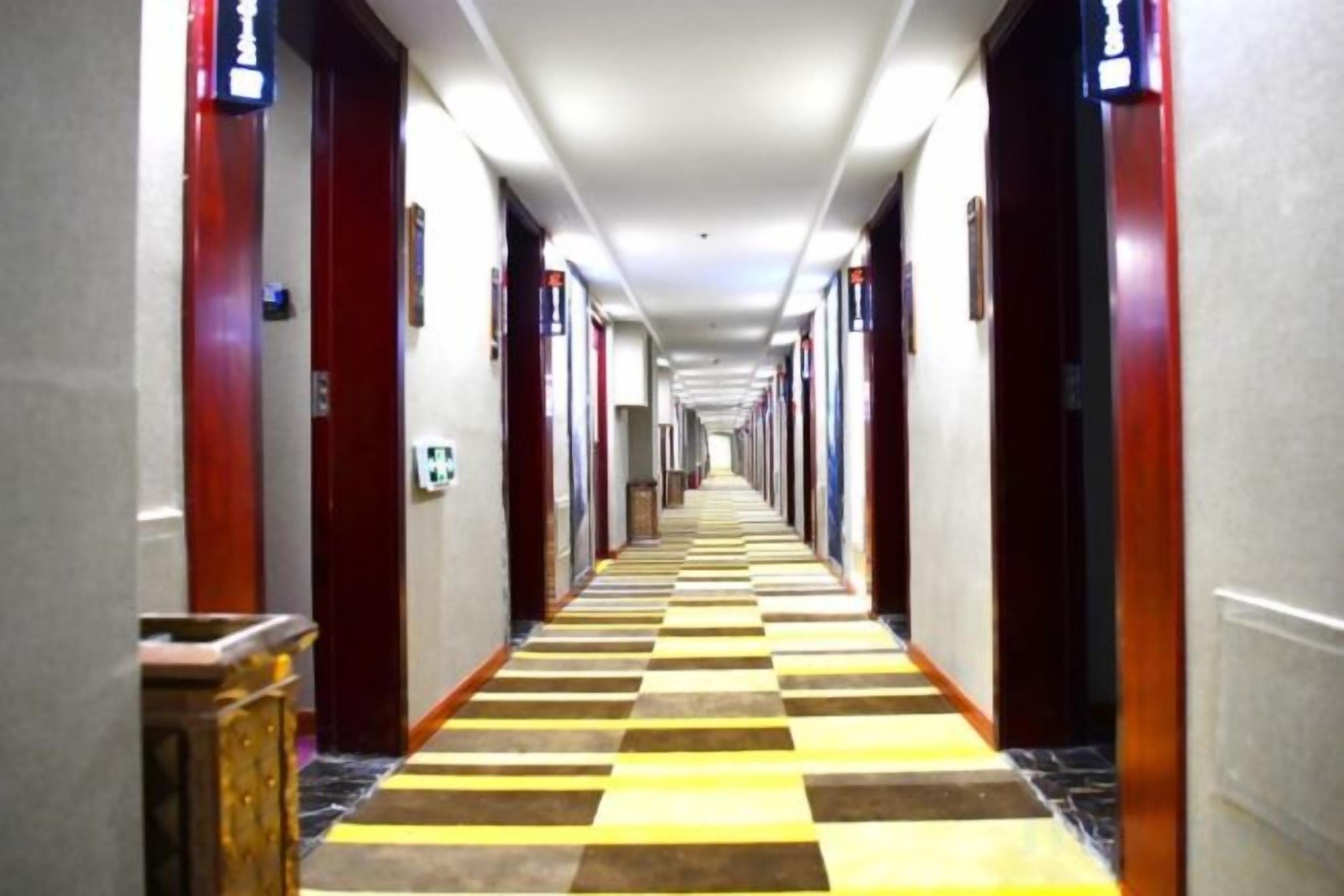 A hotel hallway with doors on both sides, a checkered floor, and a long corridor.