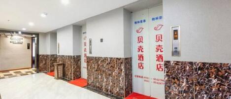 A hotel lobby with a reception desk, a red carpet, and a wall with directional signage.