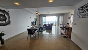 A spacious living area with a dining table, chairs, a sofa, and a bar area.