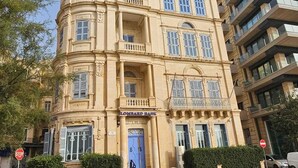A historic building with a curved facade, multiple balconies, and a prominent entrance with a blue door.