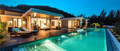 A modern house with a swimming pool, outdoor seating, and a covered patio area.