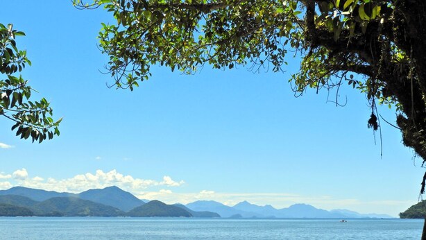 A beach with a clear view of the water and mountains in the distance. - Matira Beach 114 (Ubatuba)