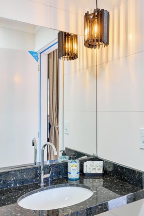 Une salle de bain moderne avec un grand miroir, un lavabo et un distributeur de serviettes.