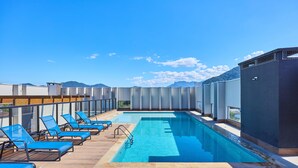 A rooftop pool with blue lounge chairs and a view of mountains. - Matira Beach 114 (Ubatuba)