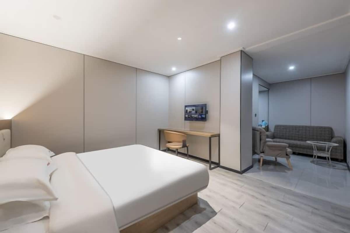 Una habitación de hotel moderna con una cama grande, un escritorio, un sofá y una mesita.
