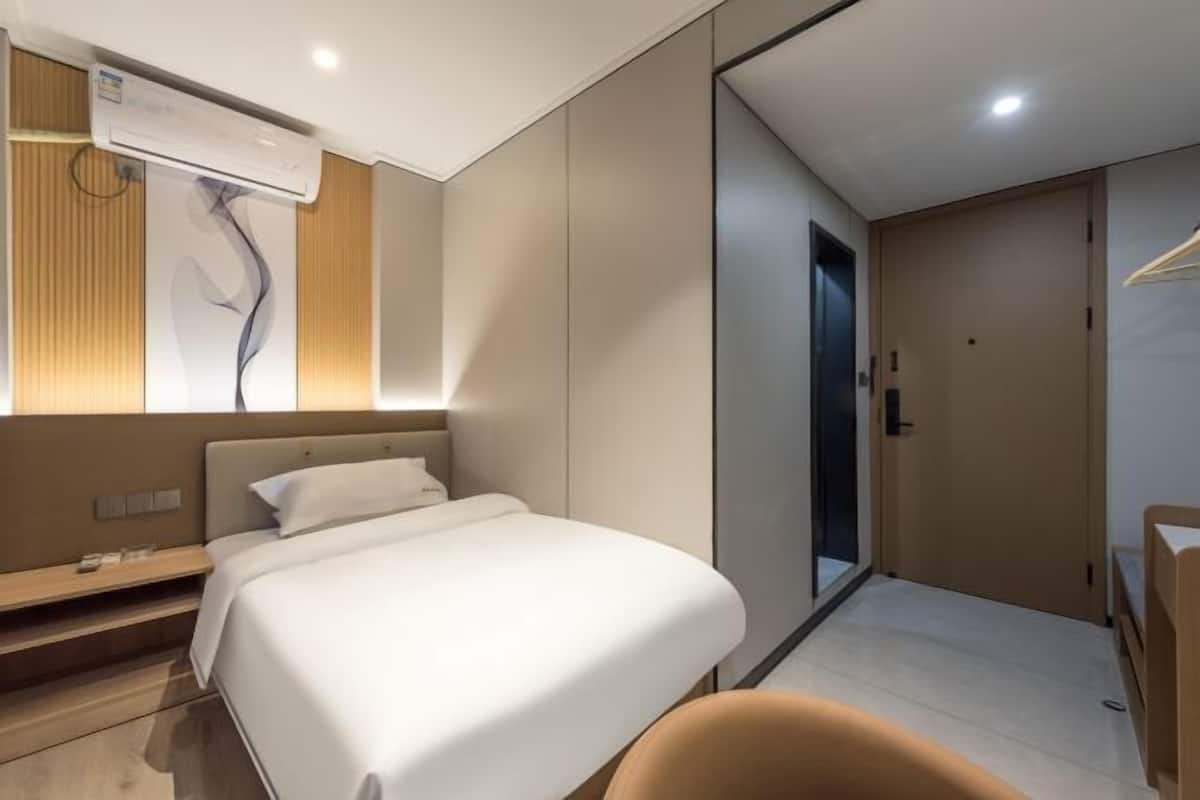 Una habitación de hotel moderna con cama, mesita de noche y espejo.