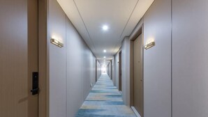 A hotel corridor with a patterned carpet, doors on both sides, and illuminated wall sconces. - Shunjie Hotel (Yuyao)