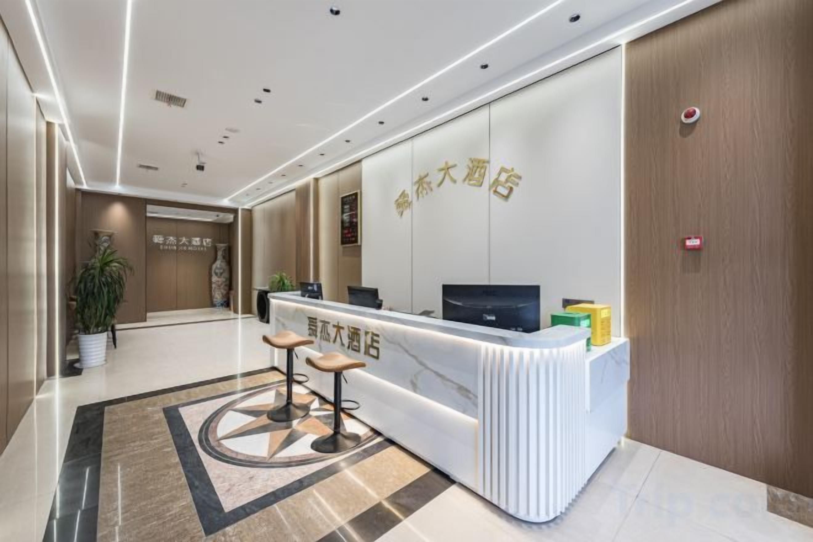 A reception area with a reception desk, two bar stools, a potted plant, and a wall-mounted television.