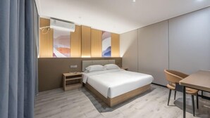 A modern hotel room with a bed, bedside table, chair, and a small desk with a chair. - Shunjie Hotel (Yuyao)