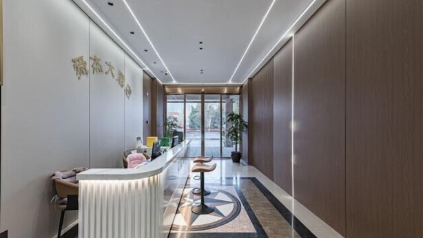 A modern reception area with a reception desk, seating, and a view through the glass doors. - Shunjie Hotel (Yuyao)