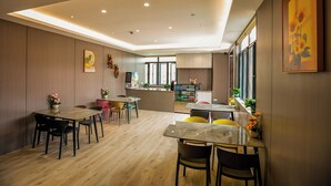 A modern dining area with wooden flooring, multiple tables, and chairs. - Ketangjian Apartment Hotel  (Shanghai)