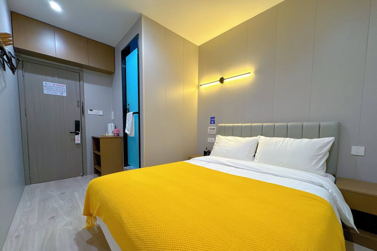 A hotel room with a bed, a desk, and a wardrobe.