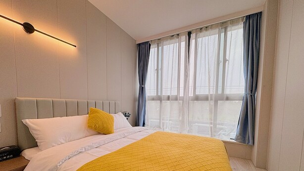 A modern hotel room with a bed, a bedside table, and a window with curtains. - Ketangjian Apartment Hotel  (Shanghai)