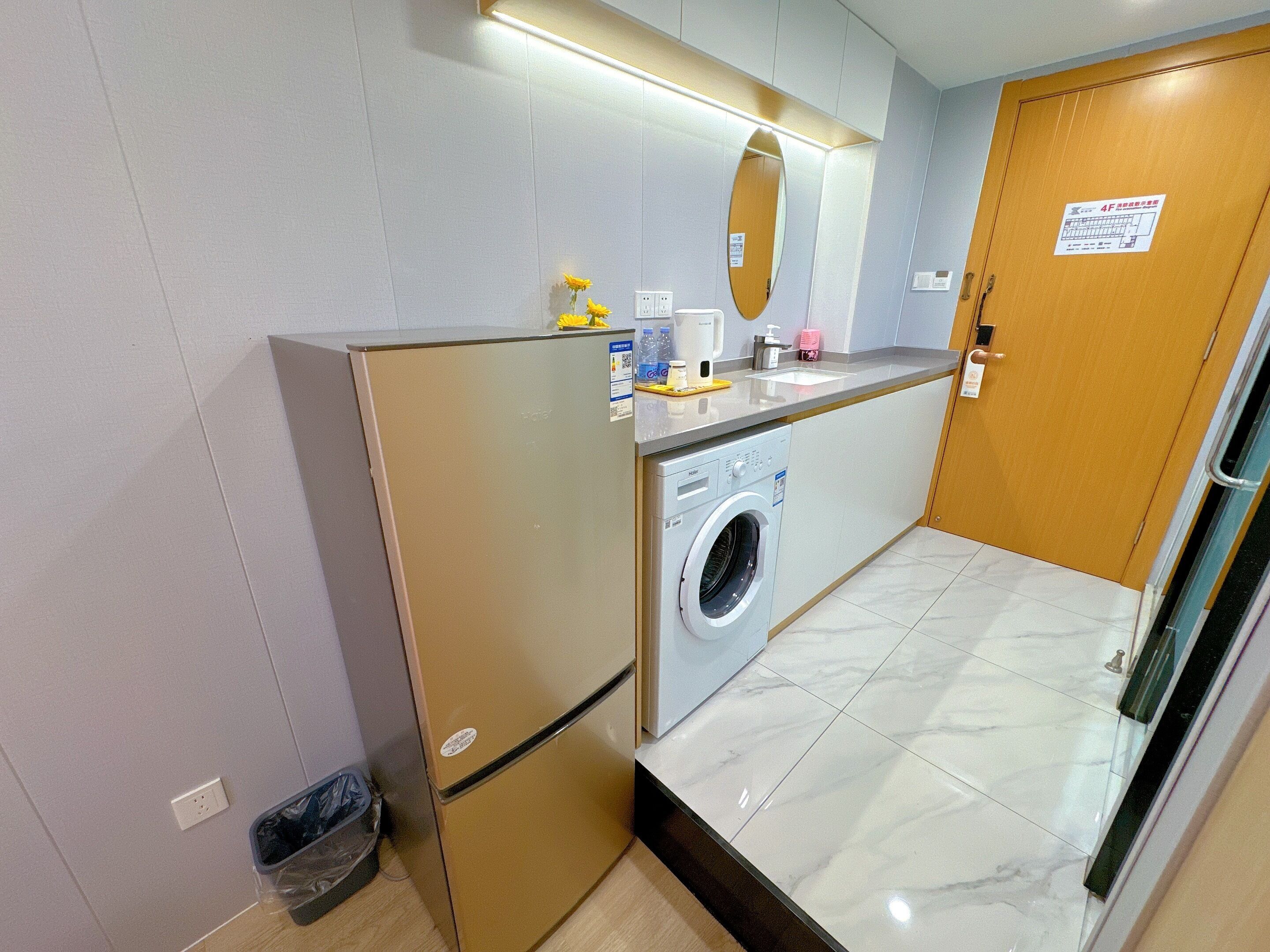 A compact kitchenette with a built-in washing machine, a small sink, and a mirror above it.