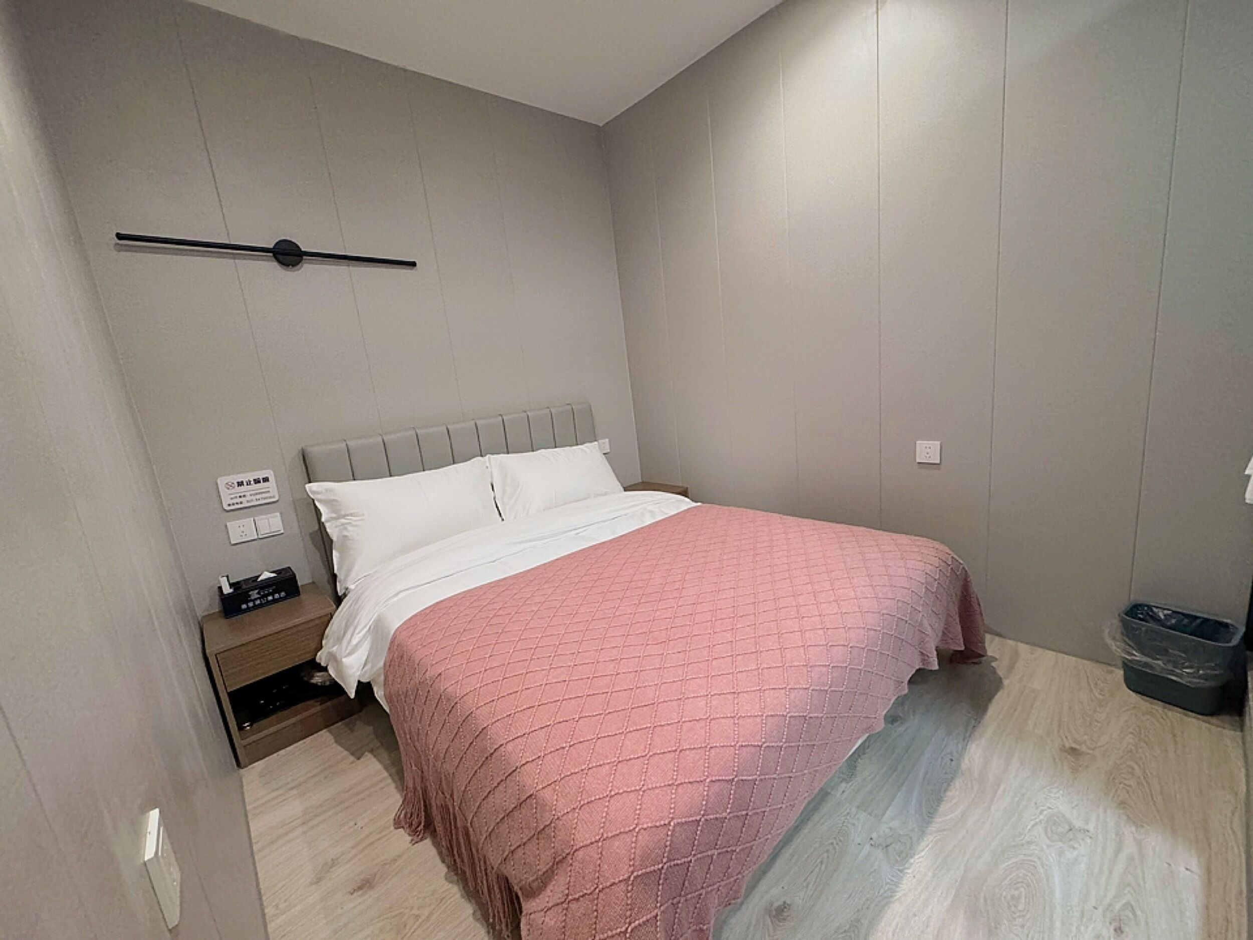 Une chambre à coucher comprenant un lit, une table de chevet et un luminaire fixé au mur.
