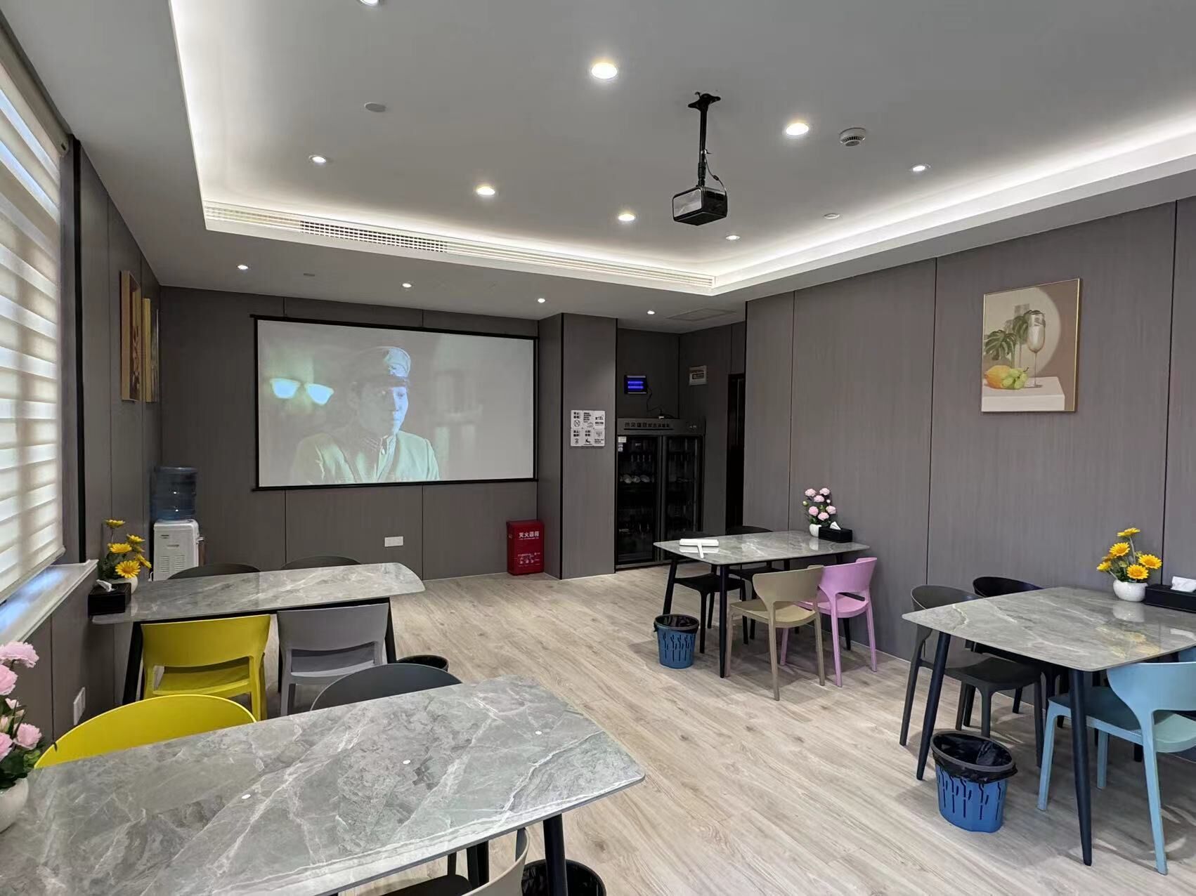 A modern conference room with a large screen, marble tables, and chairs.