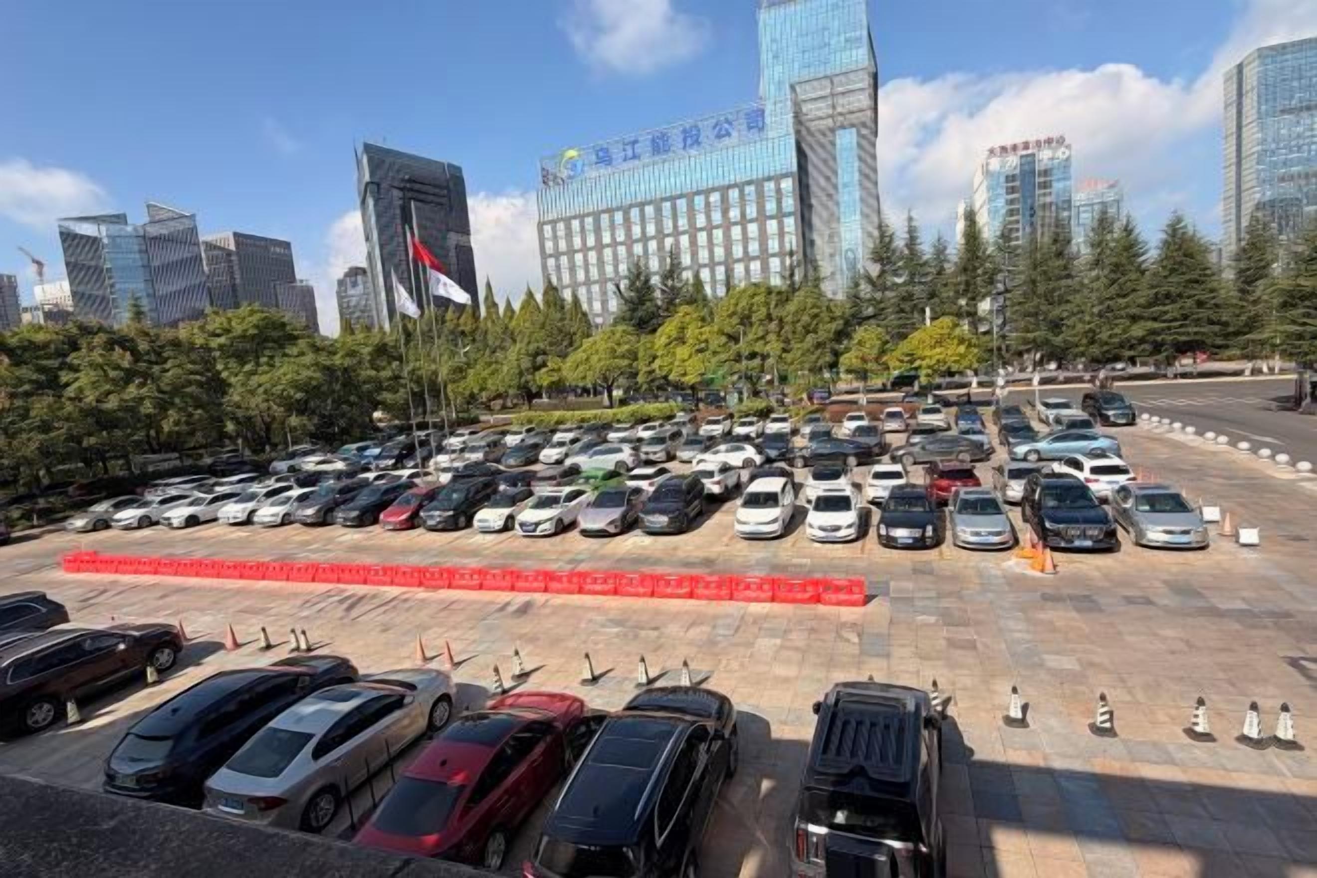 A parking lot with multiple cars, surrounded by trees and buildings.
