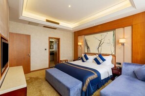 Quarto de hotel com cama, um banco, televisão e um quadro na parede.