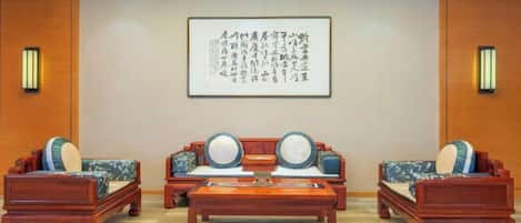 Un salón de estilo tradicional con un conjunto de sofás, una mesa de centro y una obra de arte caligráfica enmarcada en la pared.