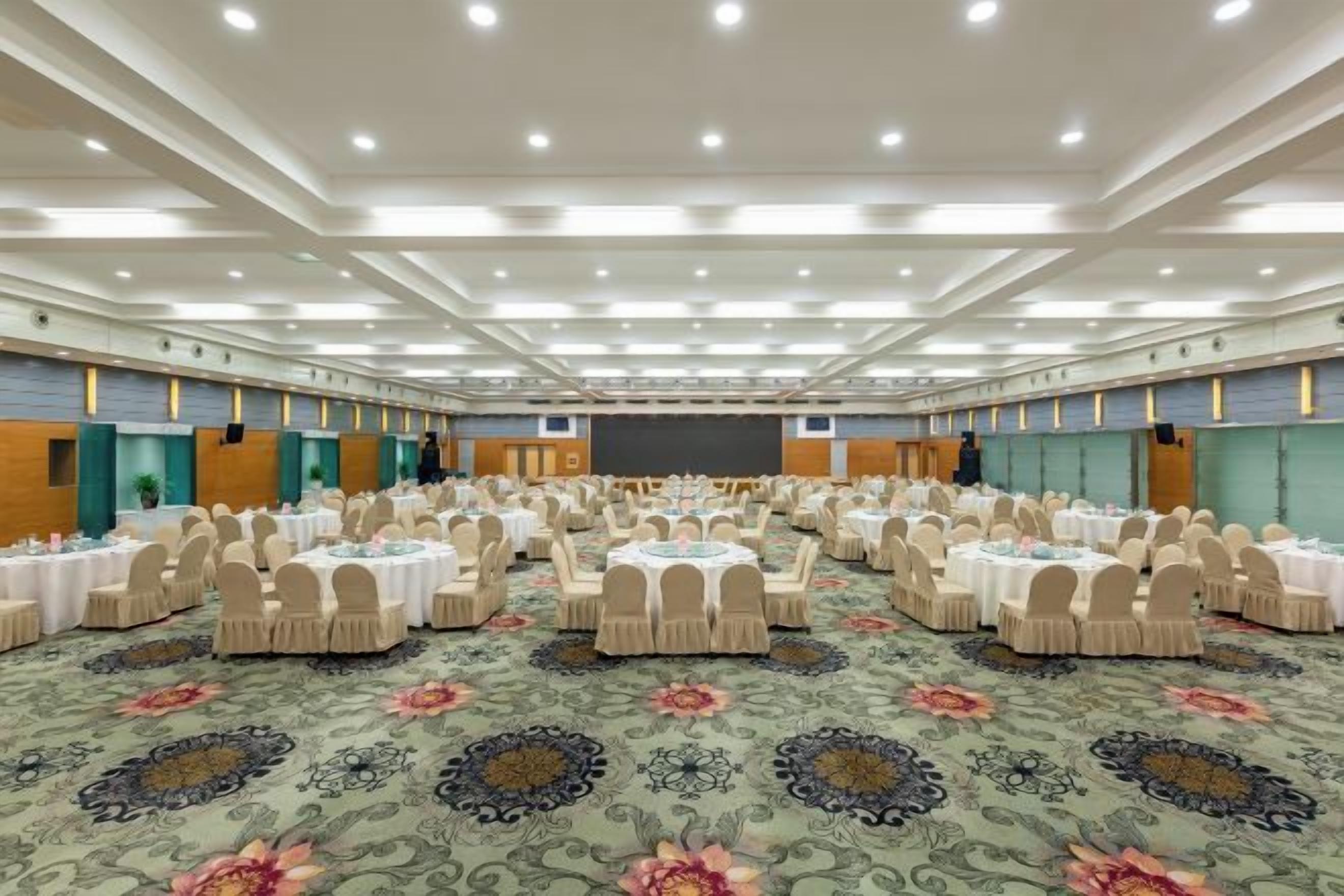 A large conference room with round tables, chairs, and a stage.