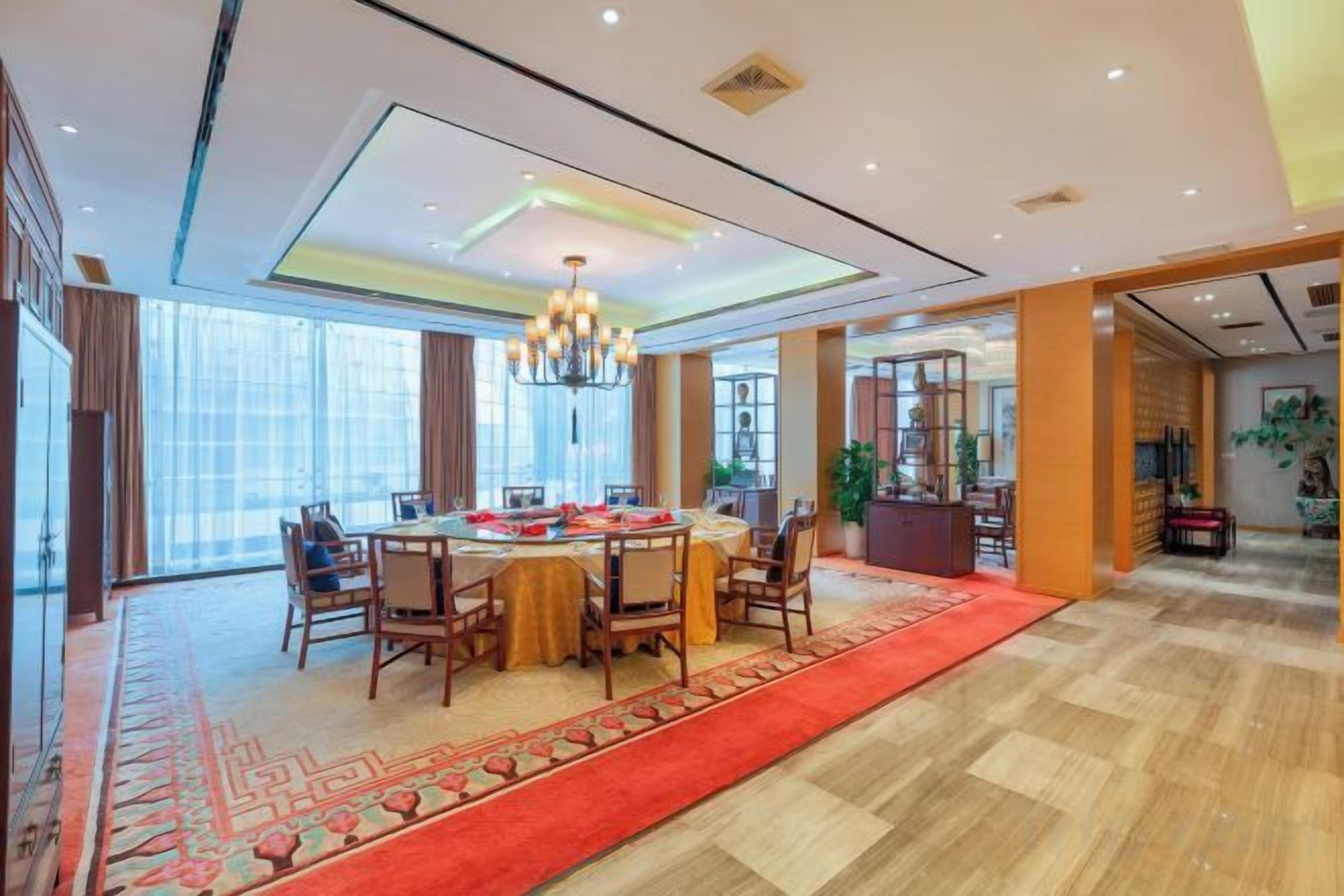 A spacious dining area with a round table, chairs, and a red carpet.