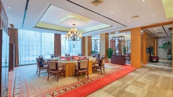 A spacious dining area with a round table, chairs, and a red carpet.
