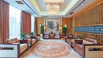 A hotel lobby with a round carpet, seating area, and decorative wall.